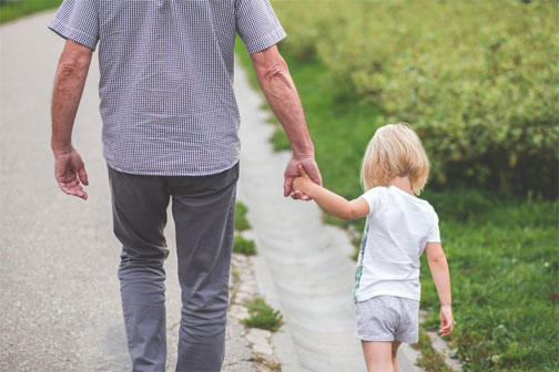 A parent and child walk together holding hands