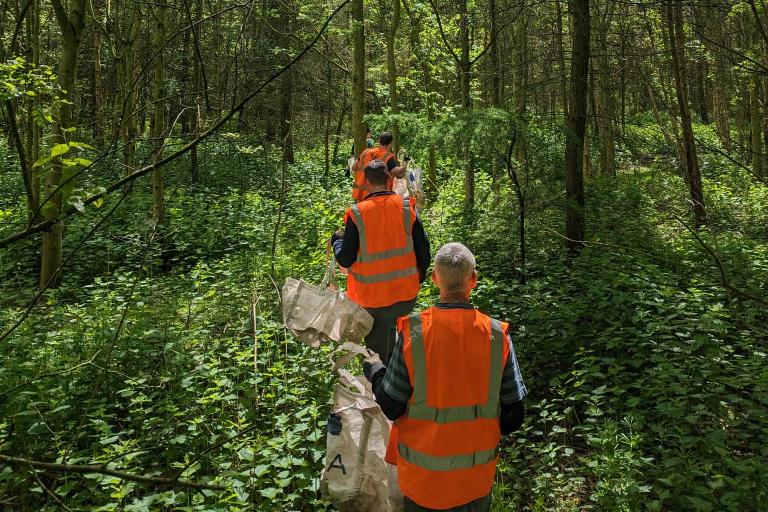 Image shows two volunteers walking along a woodland path
