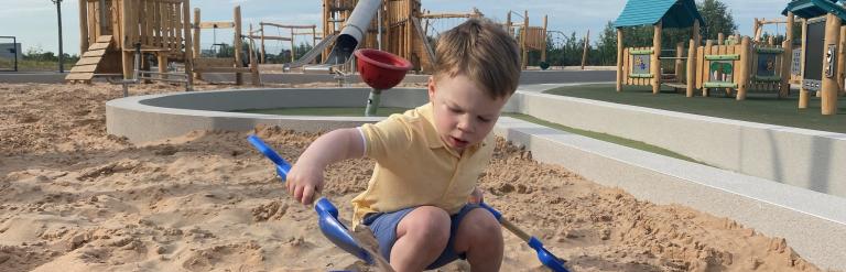 Image shows child playing with a bucket and spade in the sand at Fun Arium